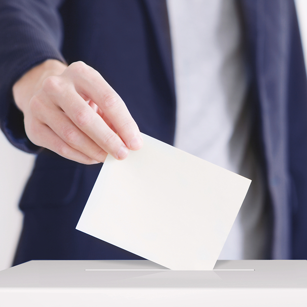 Männliche Hand wirf Stimmzettel in Urne.