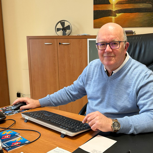 Dr. Ralf Loos Älterer Mann, Halbglatze, Brille, im Pullover am Schreibtisch, vor ihm eine PC-Tastatur. Er lächelt.