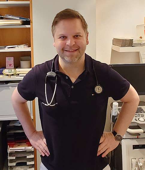 Dr. Oliver Wegener lächelt in die Kamera und stützt die Hände in die Hüfte.