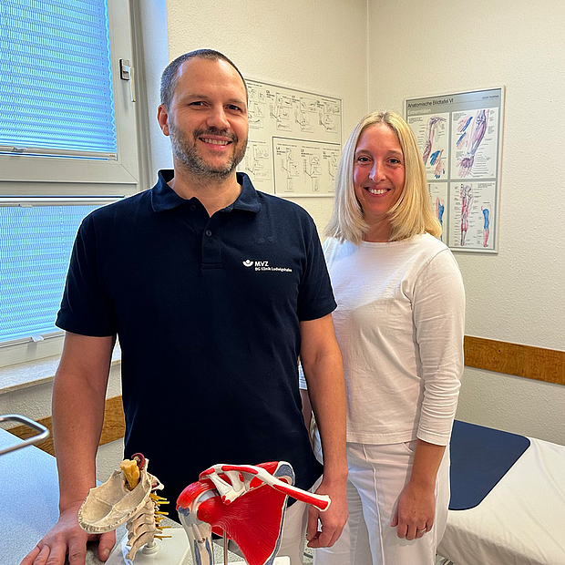 Holger Schwarz und Dr. Christina Keil Mann und Frau mittleren Alters, leger gekleidet, lächelnd nebeneinander im Behandlungsraum