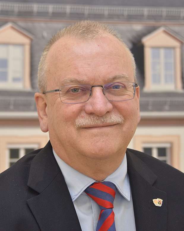Dr. Günther Matheis Älterer Herr mit Brille (Portrait), er lächelt in die Kamera und trägt einen Anzug.
